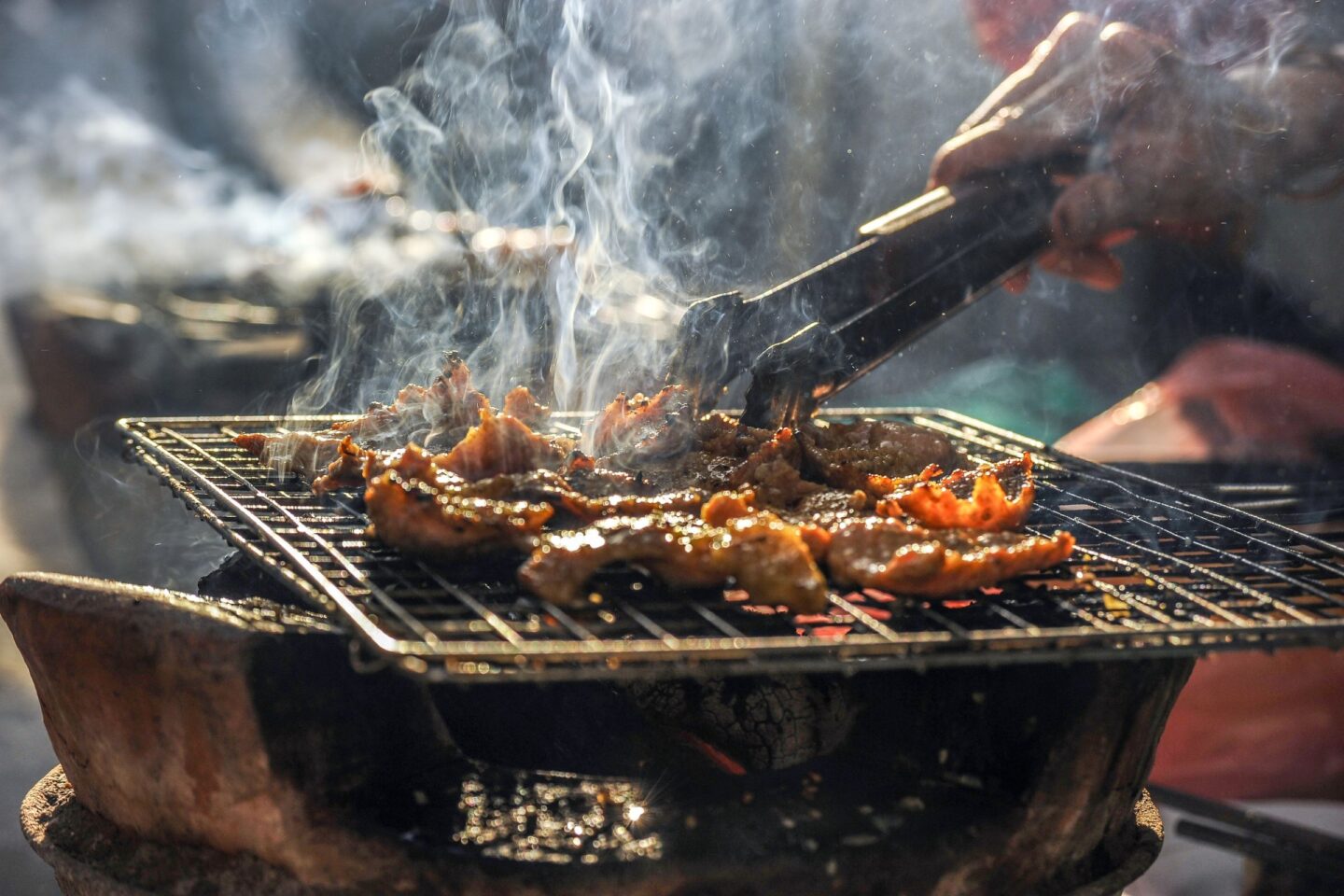 Man grilling meat with wood